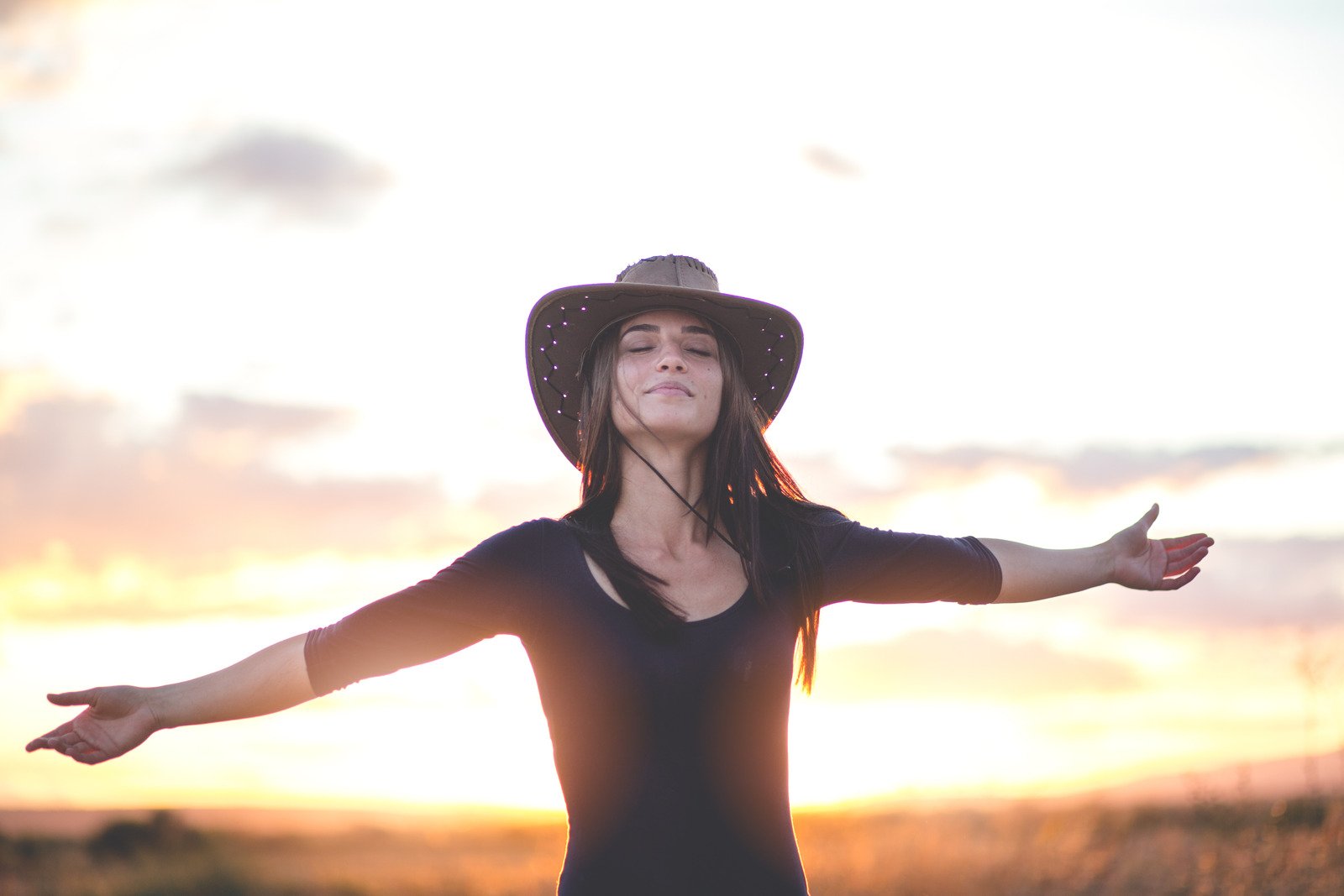 Mujer libre con los brazos abiertos al atardecer