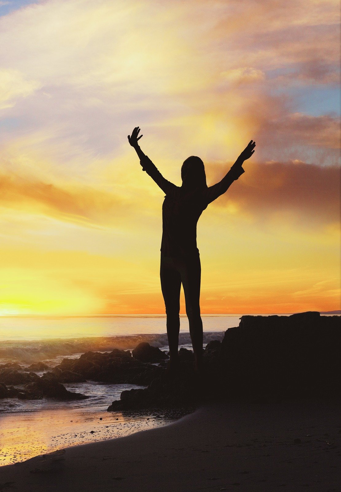 Silueta de persona con brazos levantados al atardecer - Transformación